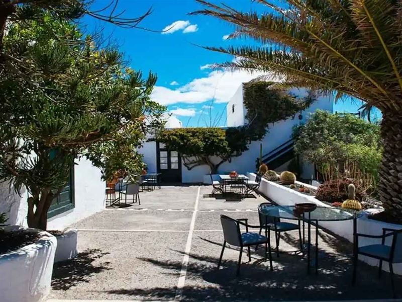 Terrasse de l'Hôtel El Grifo à Lanzarote, murs blancs, palmiers et tables sous le soleil